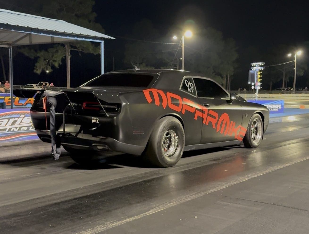 A black muscle car with red "McFarlan" lettering at night.