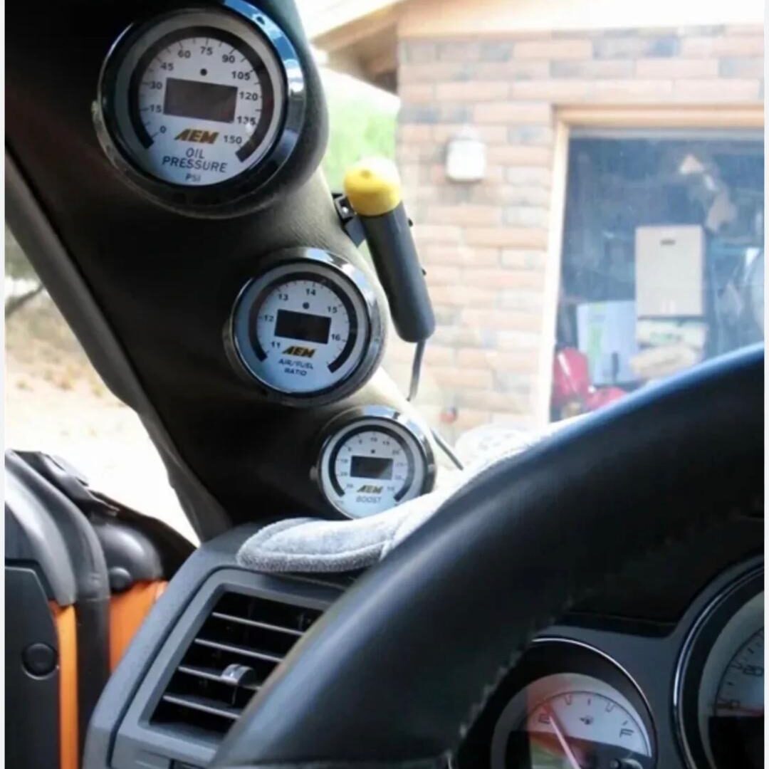 Close-up of a car dashboard with gauges and a steering wheel.