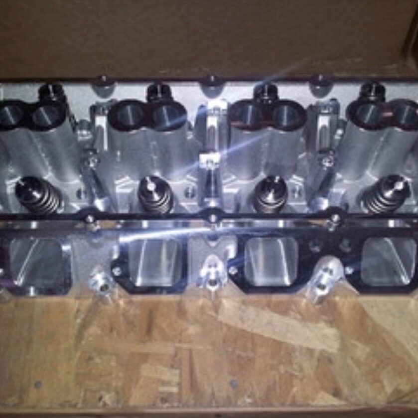 Close-up of a metallic engine cylinder head on a wooden surface.