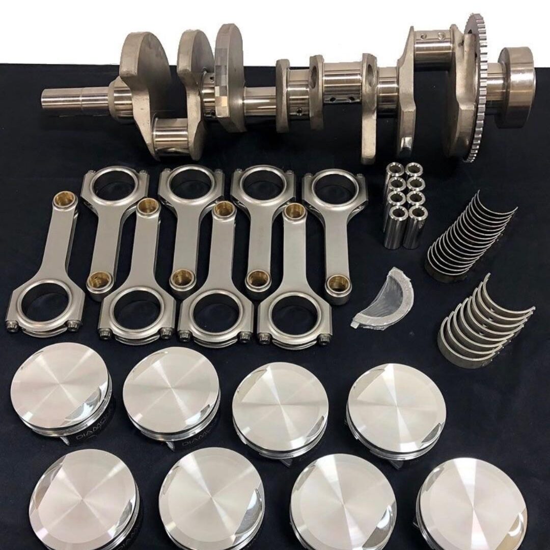 Engine pistons, connecting rods, and crankshaft parts laid out neatly.